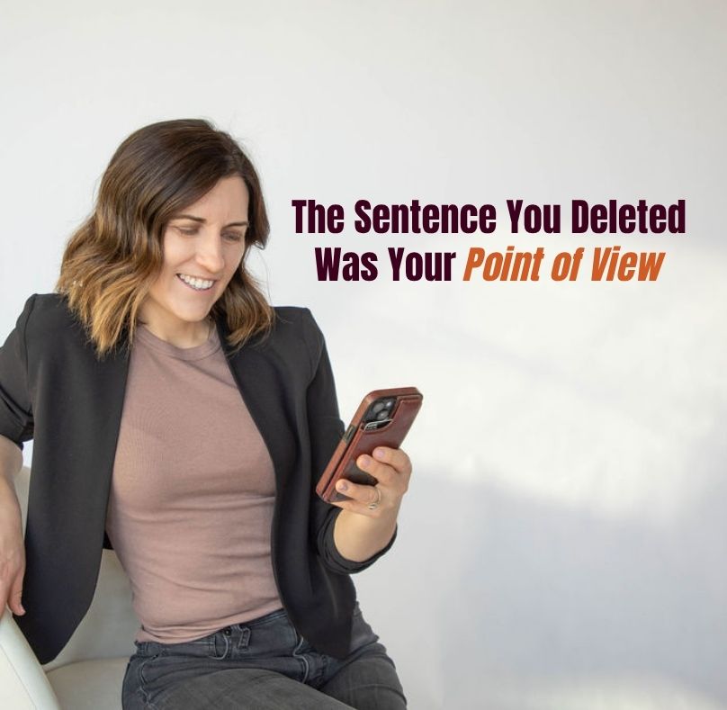 Woman in a black blazer smiling at her phone, with text overlay reading "The Sentence You Deleted Was Your Point of View"